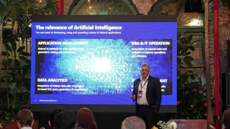 Guido Falkenberg speaking in front of a blue slide with an image of computer hardware at a Software AG event. 